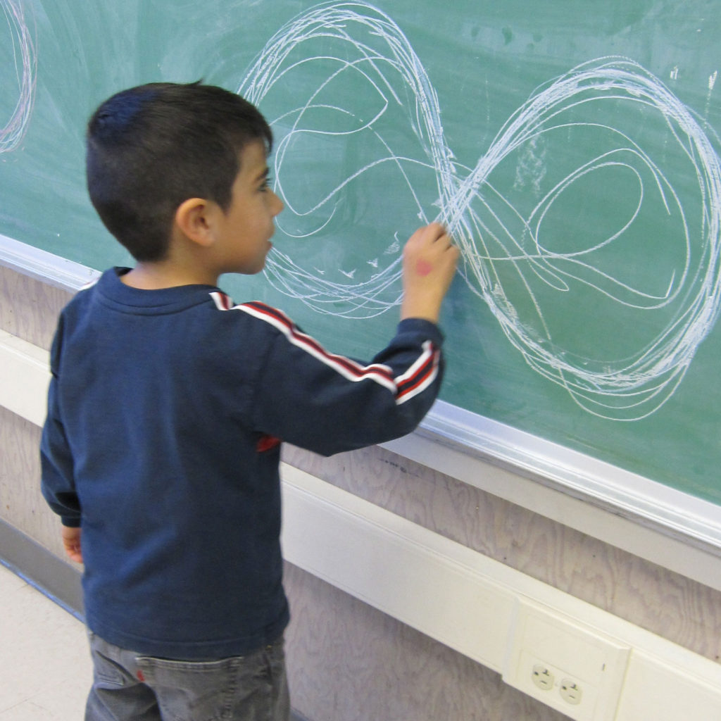 child drawing on blackboard